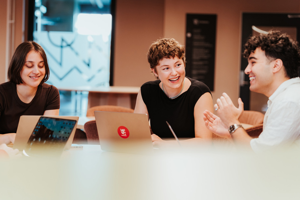 Tre studenter sitter sammen og jobber.