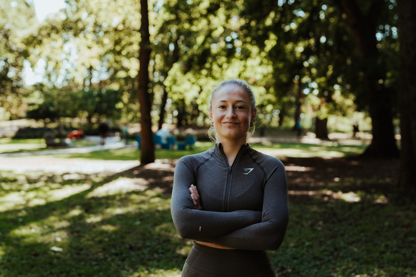 Student i treningstøy står i en park en vårdag.