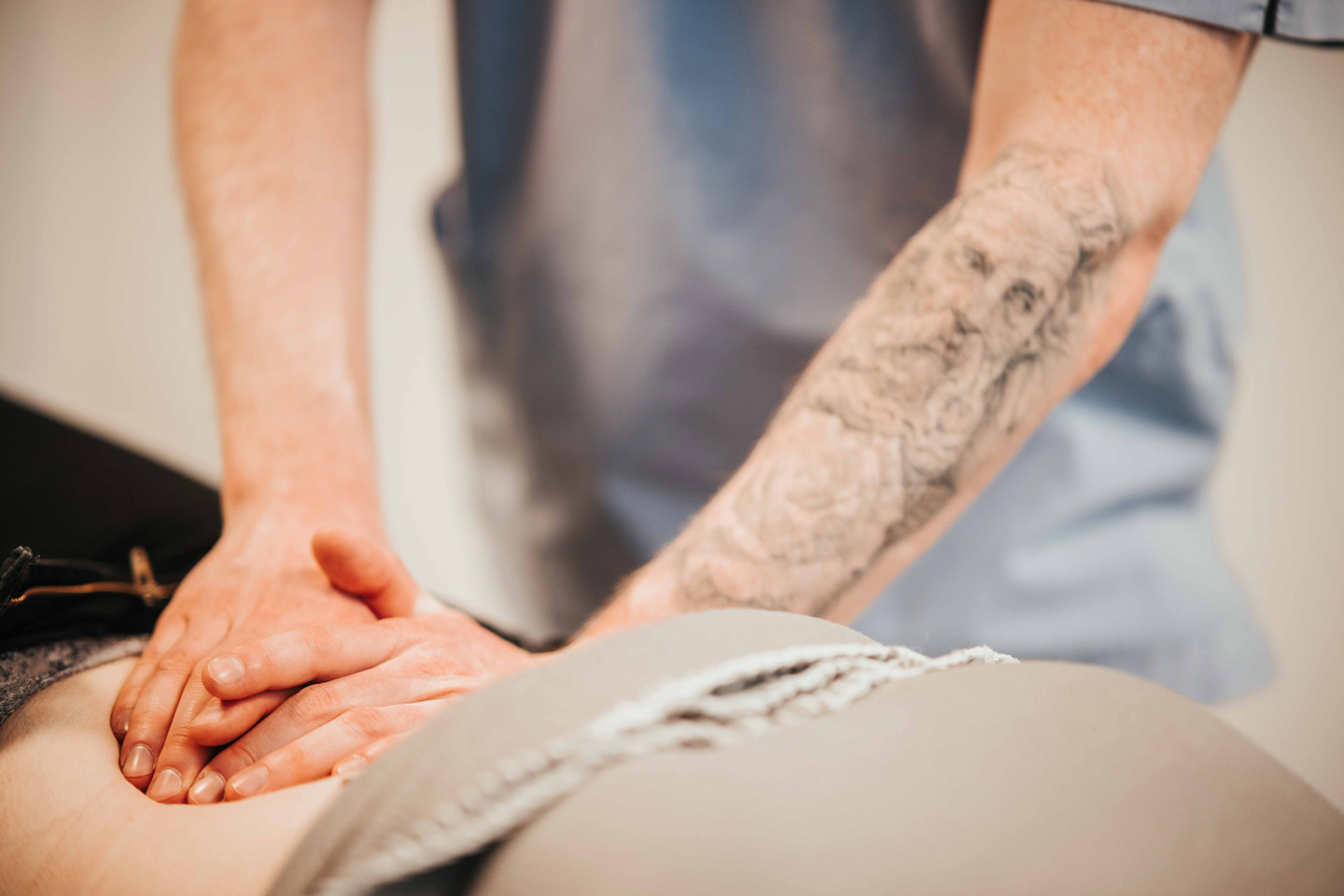 Hender som trykker på ryggen til en pasient.