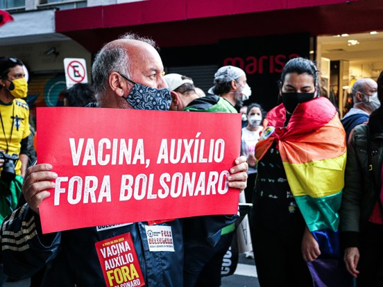 Man wearing face mask and holding sign against Bolsonaro