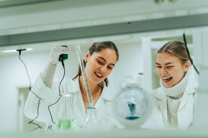 To studenter i hvite frakker på biolab.