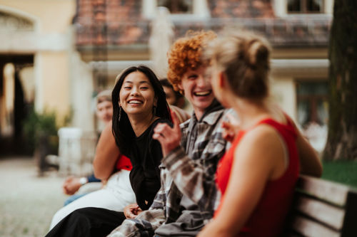 Bildelenke av studenter som sitter på en benk, til en side om sosialt miljø på Kristiania.