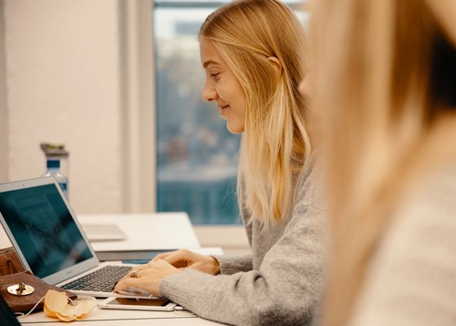 Foto av to kvinnelige studenter som samarbeider på en laptop.