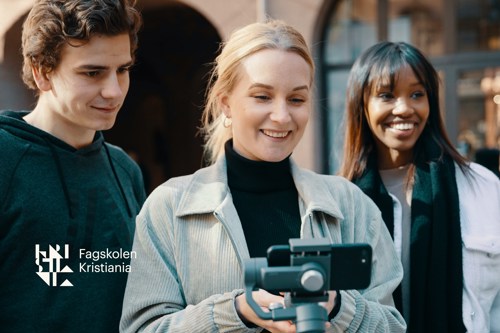 Tre fagskolestudenter står sammen, der hun i midten holder en telefon på en gimbal. 