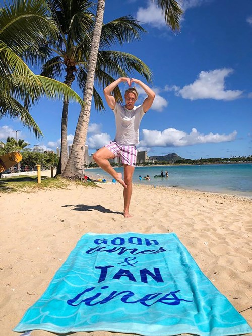 Mann på strand balanserer på en fot.