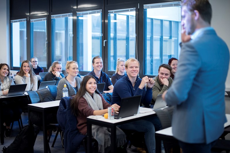 Foreleser på Høyskolen Kristiania som står foran en engasjert klasse. 