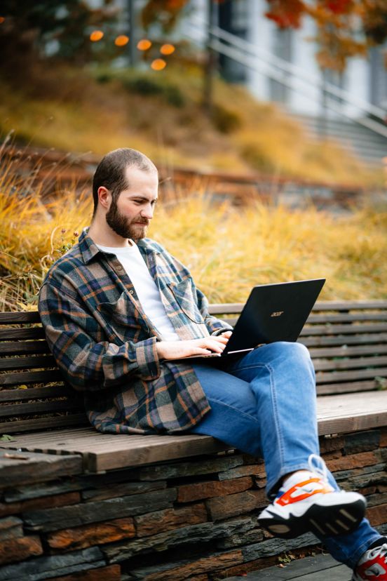 Man jobber med PC på en parkbenk.