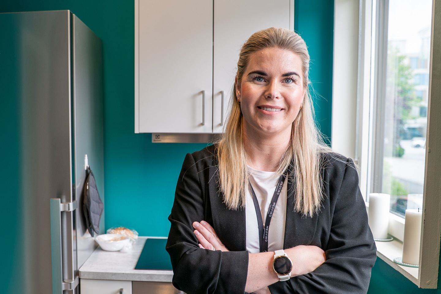 Portrett av Ragnhild på et kjøkken, med kjøleskap og komfyr i bakgrunnen.