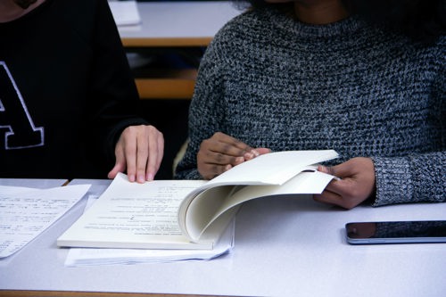 Studenter blar i pensumbok.