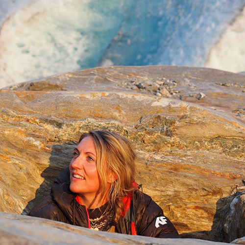 Foto av Maria som sitter foran en stor stein i fjellet.