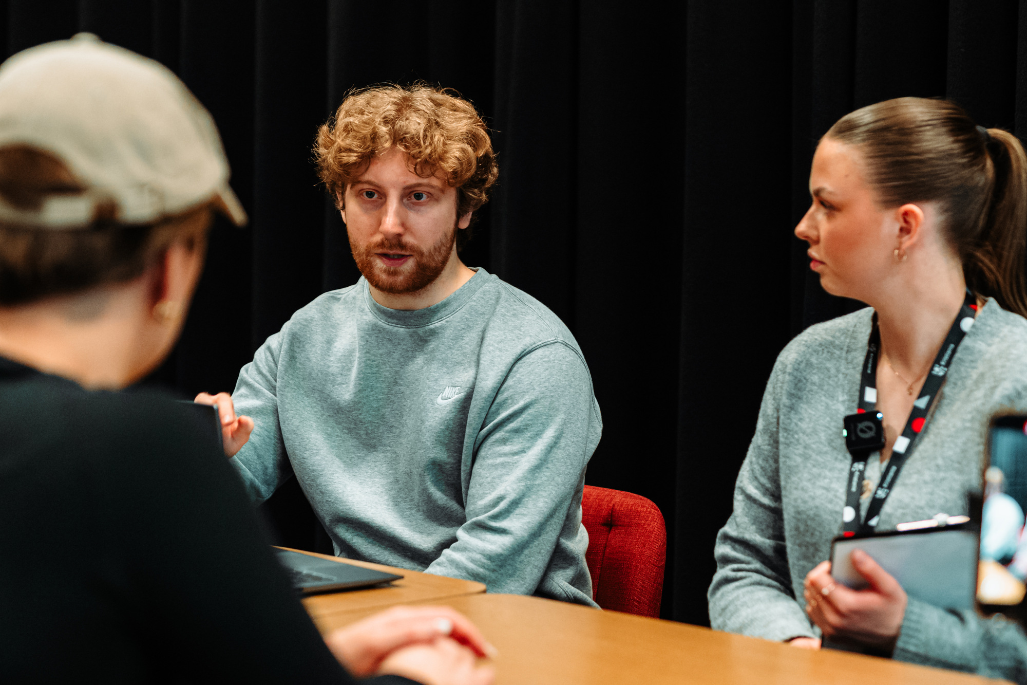 Fredrik og Gine sitter ved et bord og gir tilbakemeldinger på helsekartleggingen til Mathilde Ullum.
