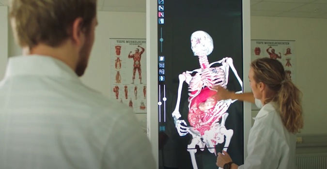 To personer ser på en skjerm som viser bilde av et menneskelig skjelett.