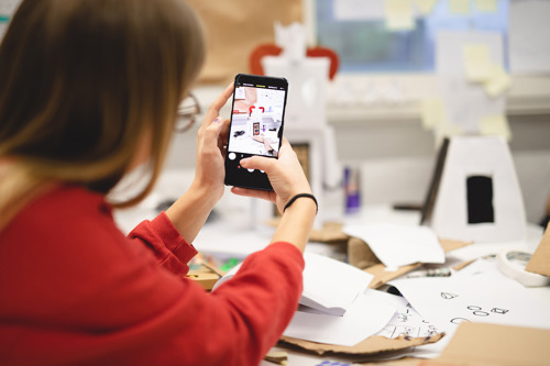 Foto av en kvinne som tar bilde av en figur med en mobiltelefon.