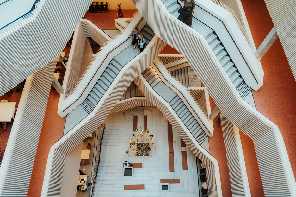 Looking down from the top floor of a modern building, multiple staircases intertwine below, creating a striking visual of geometric patterns and dynamic movement.