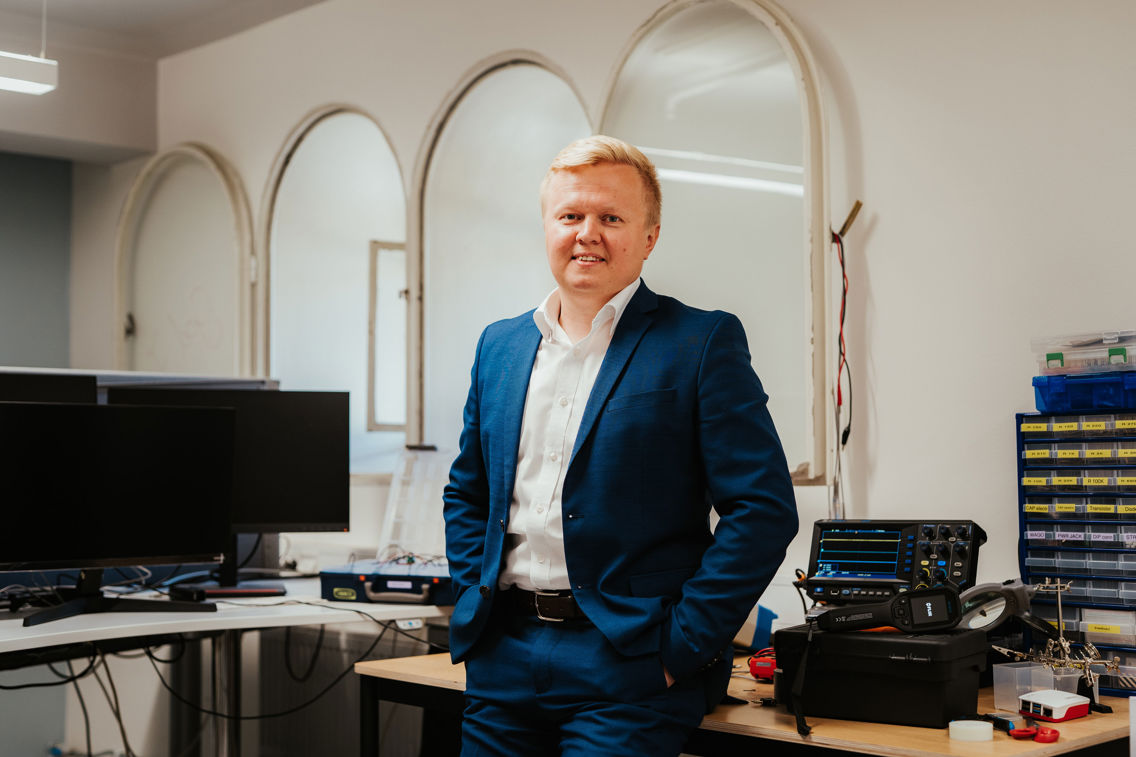 Associate professor Andrii Shalaginov is posing in front of a table full of cyber security equipment