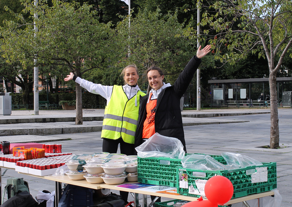 To jenter fra studentunionen står bak et bord fult av diverse mat og drikke til de som deltok i innsamlingsløpet. 