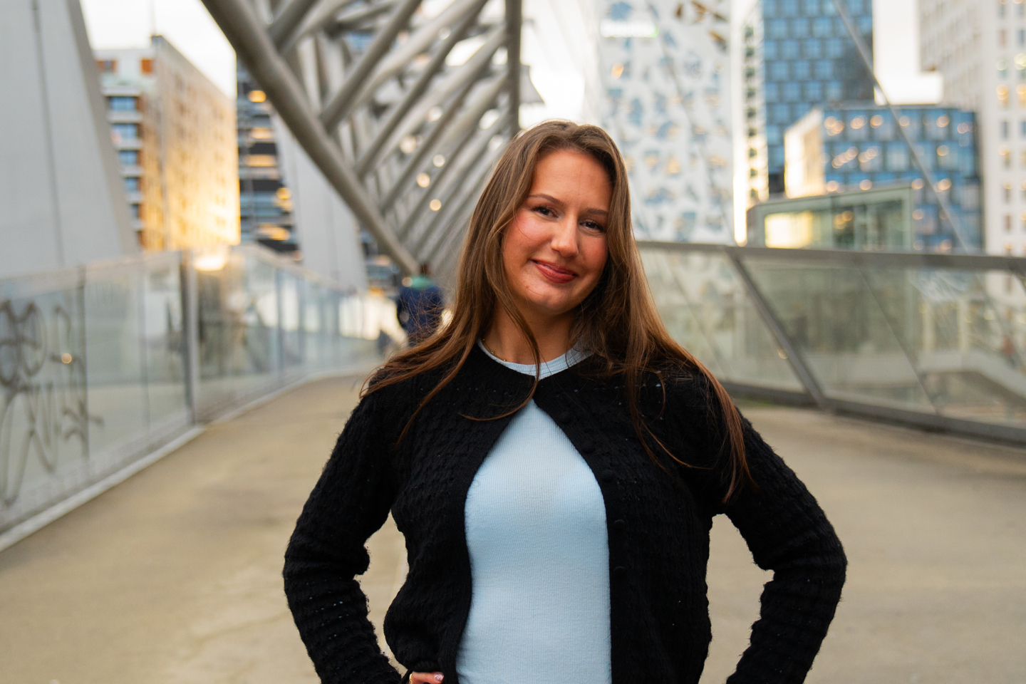 Jule står på en bro med hendene på hoften over Oslo S.