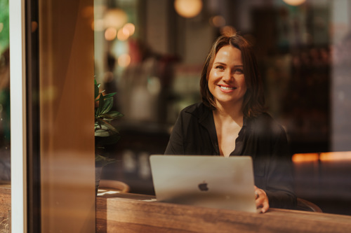 Voksen student med mac på kafé.
