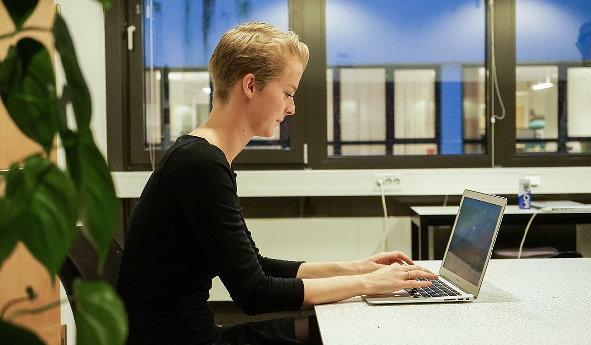 Kjersti sitter på skolen og skriver på PC-en ved et bord