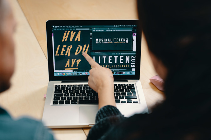 To personer ser på en dataskjerm. Personen til høyre peker på skjermen.