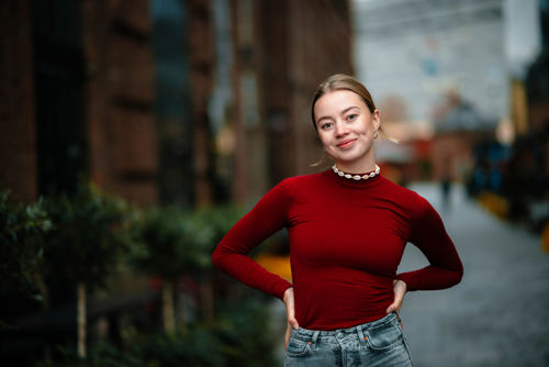 Ung kvinne med hendene i siden smiler selvsikkert