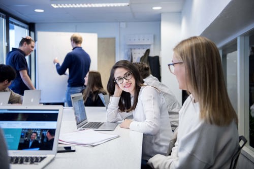 Foto av studenter som sitter ved bordet og jobber sammen.