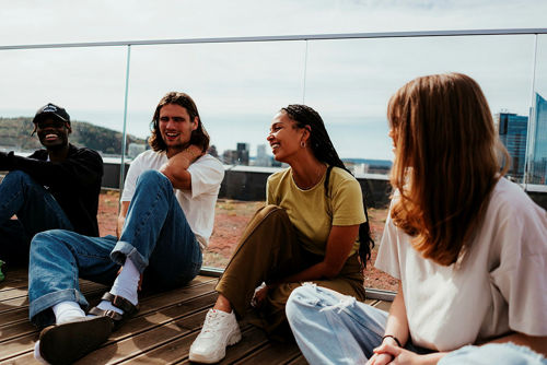 Fire studenter som sitter inntil glassgelenderet på takterrassen til Urtegata i Oslo