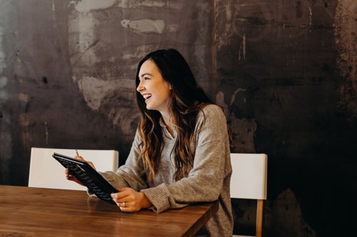 Smilende dame med ipad på jobben