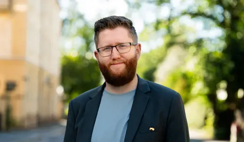 Teknologidirektør Christian Iversen står utenfor kontoret sitt i Oslo og smiler til kameraet