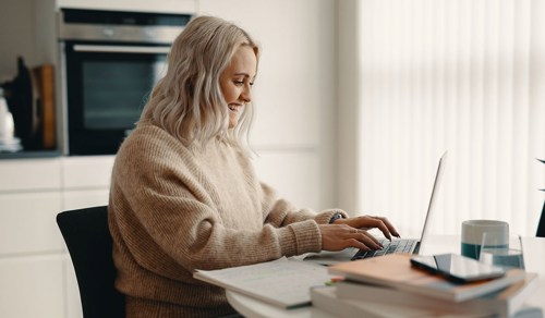 Kvinne fotografert ved skrivebord mens hun skriver på en PC