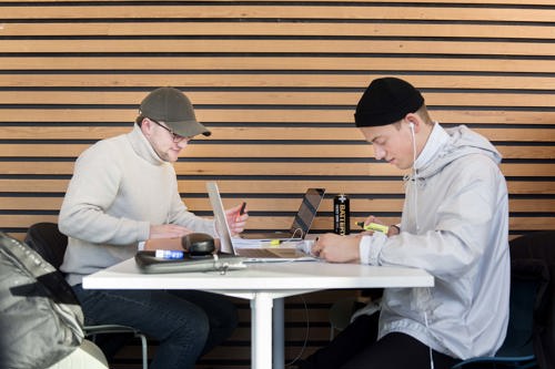 Foto av to mannlige studenter ved et bord.