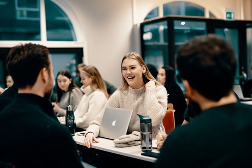 Studenter snakker sammen rundt et bord. Bachelor ledelse og servicestrategi.