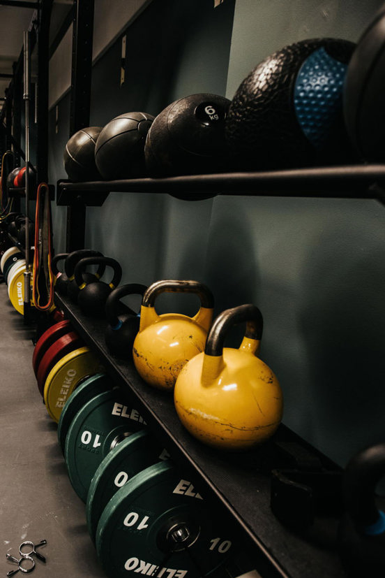 Medisinballer, vekter og kettlebells på et stativ.