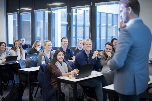 Bilde av studenter i forelesning som ser opp mot foreleser.