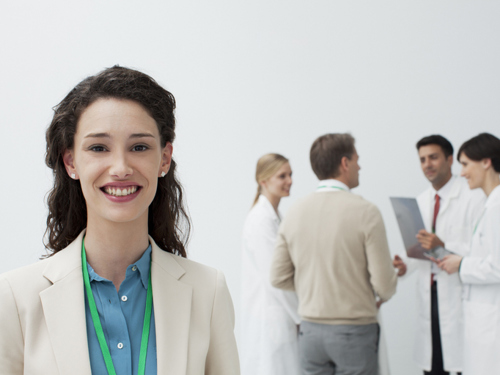 Portrait of smiling businesswoman with doctors in background