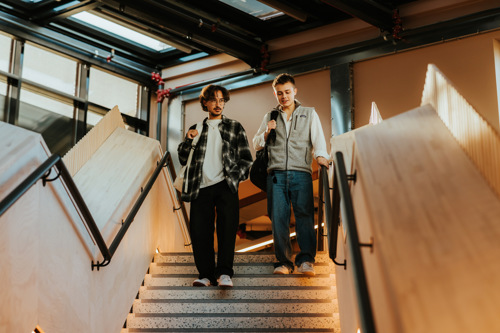 To studenter på Bachelor i anvendt psykologi går ned en trapp.