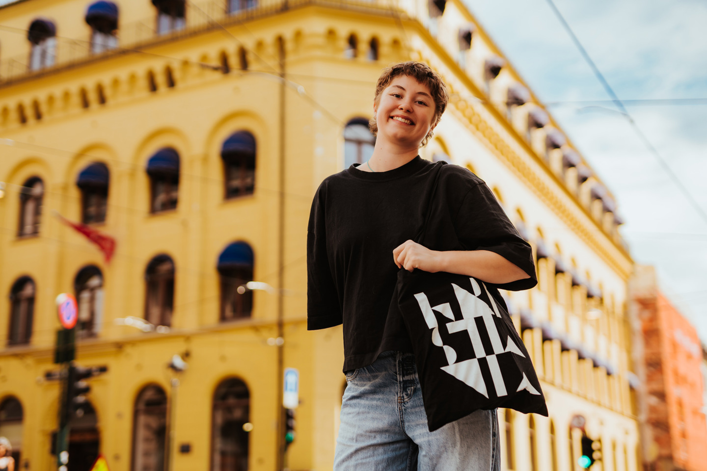 Kvinne med svart t-skjorte holder et Kristiania-nett foran Kristianias campus Kvadraturen i Oslo