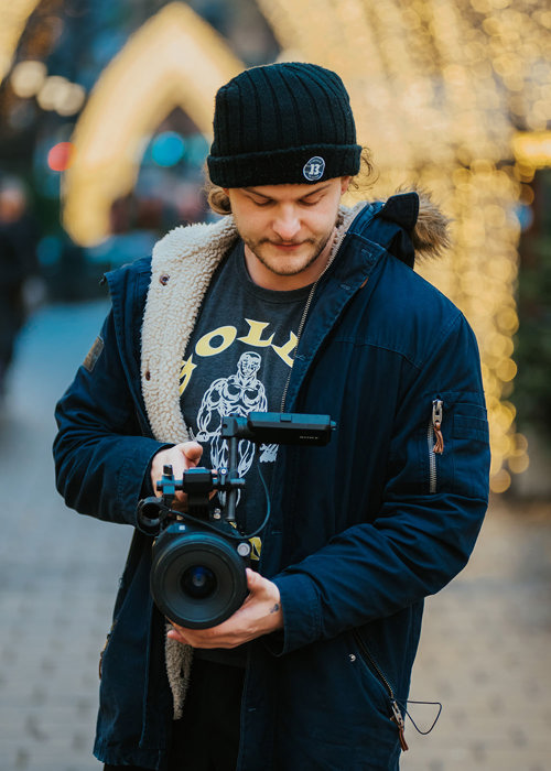 Foto av Tommy Garland som står ute og holder et kamera i hendene