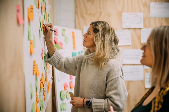 Foreleser tegner på vegg med post-it-lapper.