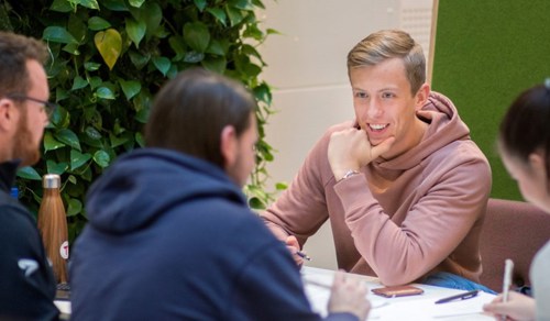 Ung mann i rosa hettegenser ser på medstudenter