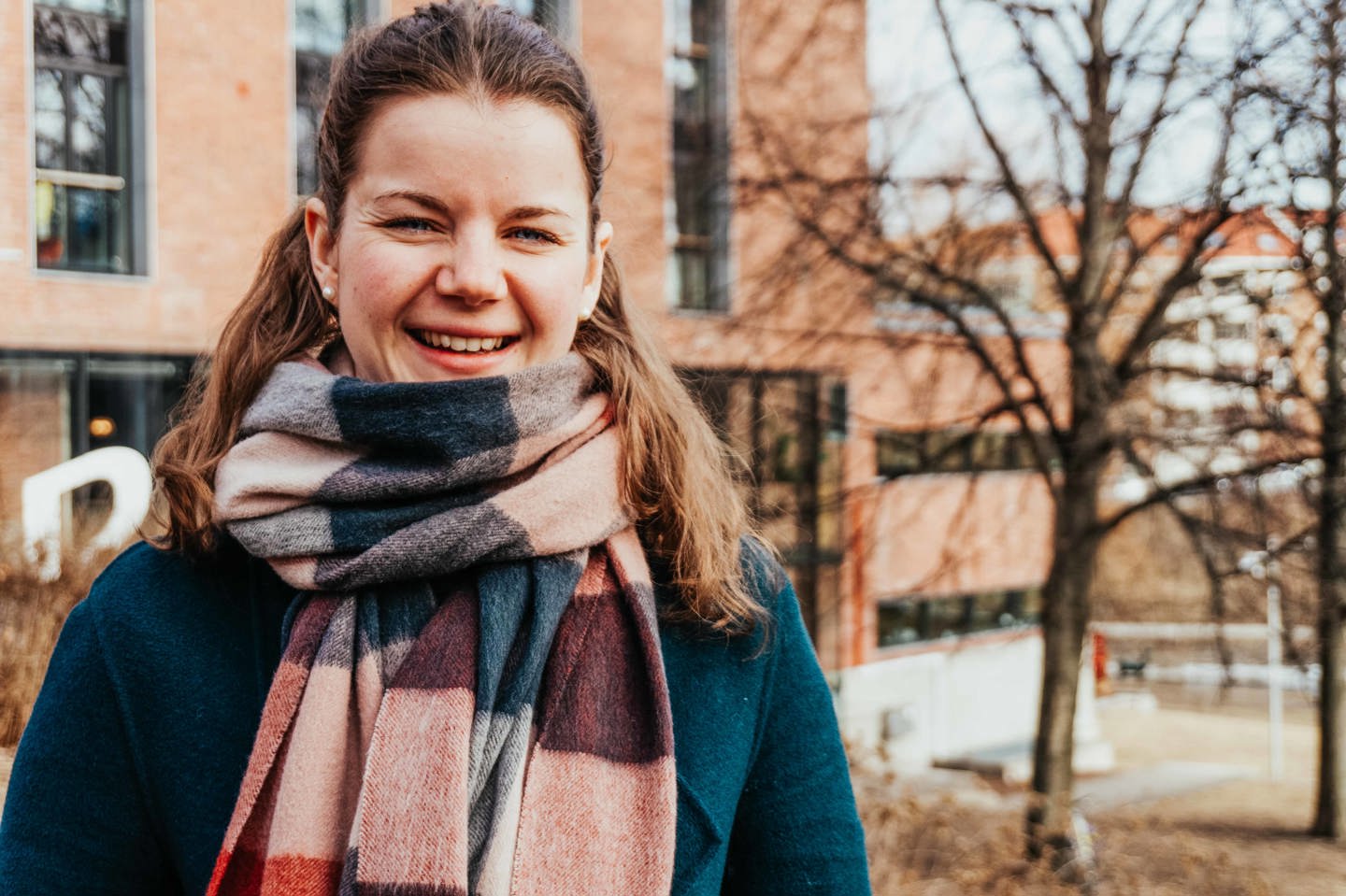 Kvinne med brunt hår og fargerikt skjerf smiler