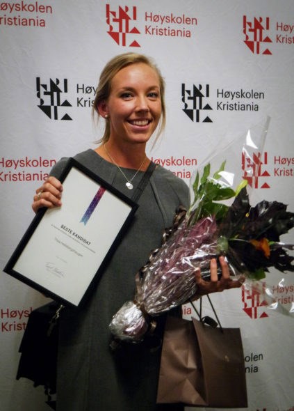 Foto av Sam som holder diplom og blomster for beste kandidat.