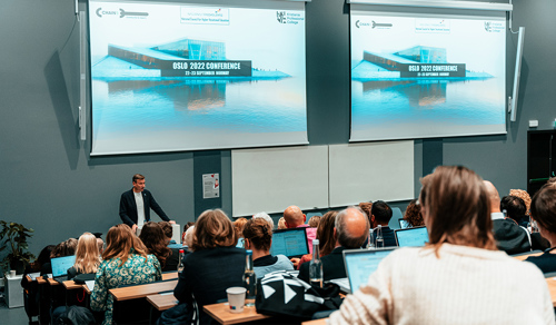 Bilde av Henrik Asheim som taler for et publikum på en konferanse.