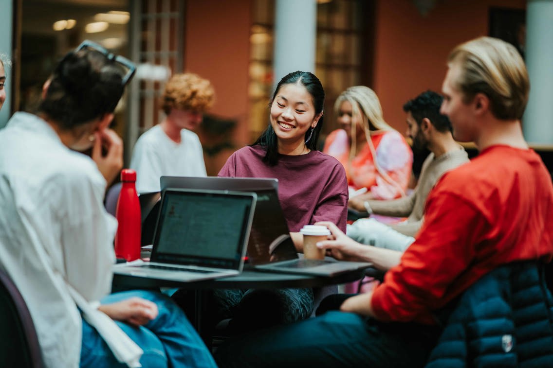 Bilde av studenter som jobber med oppgaver på et av skolens mange fellesområder.