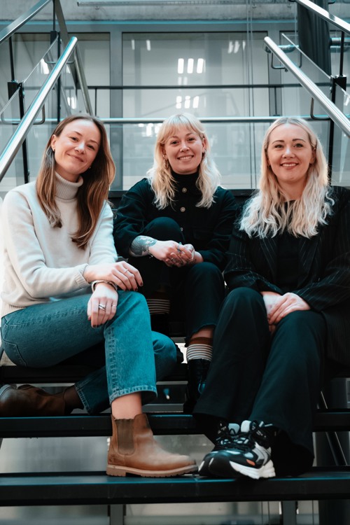 Helene, Victoria og Elise sitter i en trapp på campus Spikersuppa