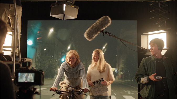 Studenter med sykkel foran greenscreen.