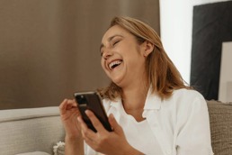 Woman laughing at something on her phone.