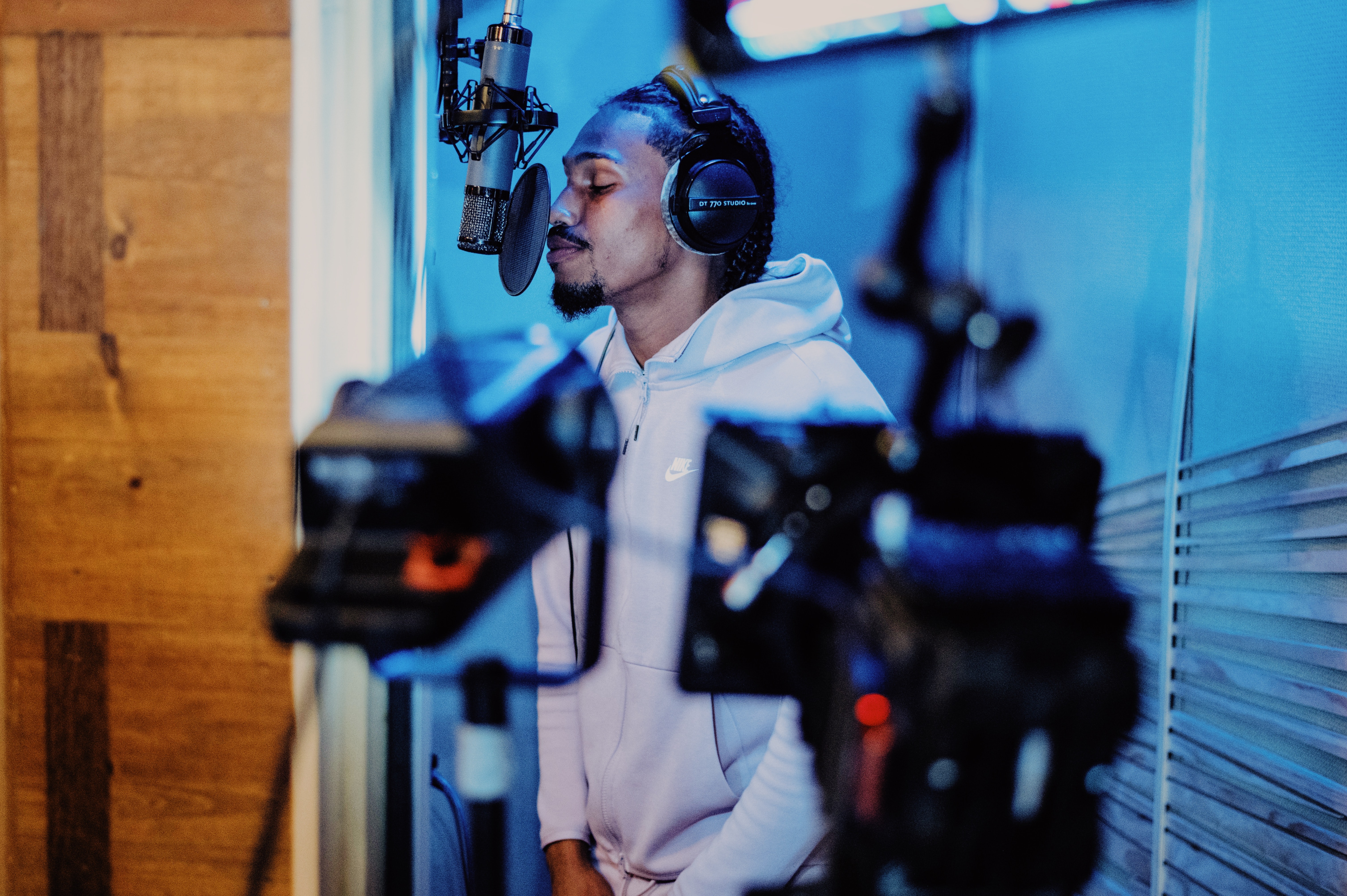 A young man is standing in the studio singing.