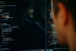 A man sitting in front of a computer full of programming.