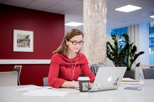 kvinne i rød genser som sitter på en laptop